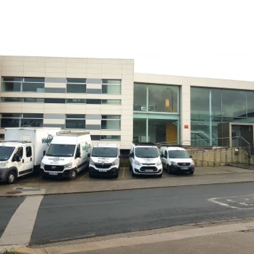 Fachada del exterior de la sede con vehículos de empresa