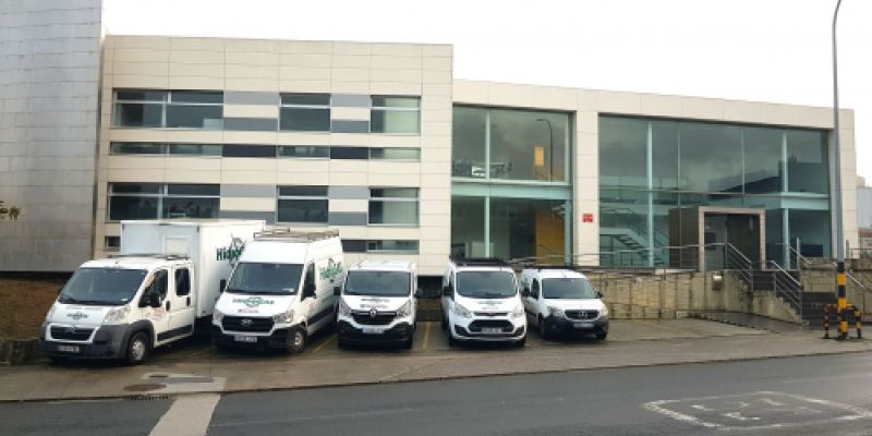 Fachada del exterior de la sede con vehículos de empresa
